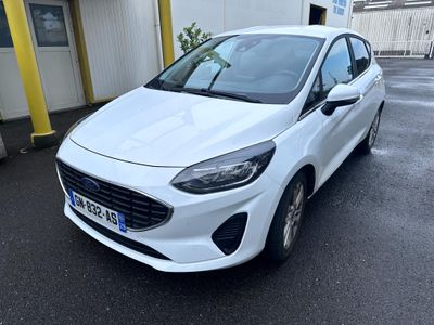 une voiture blanche garée dans un parking à côté d'un bâtiment