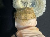 a doll that is wearing a hat with a feather on it