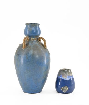 a blue vase with a rope handle next to a blue vase
