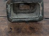 a metal object on a wooden table with a white wall in the background