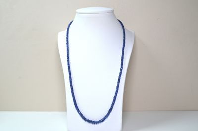 collier de perles bleues sur un mannequin à socle blanc