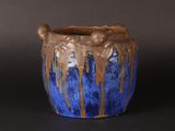 a blue and brown vase on a black surface