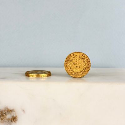 une pièce d'or posée à côté d'une autre pièce d'or sur un comptoir en marbre