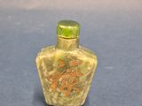 yellow jade snuff bottle with chinese writing on it on a blue surface