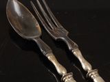 two forks and a spoon on a table with a black background