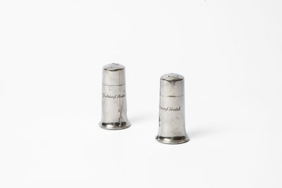 une paire de salières et poivrières en argent posées sur une surface blanche