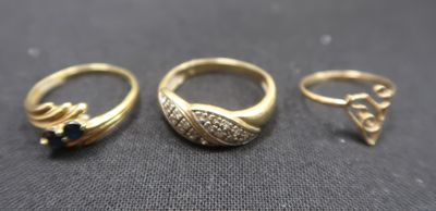 three gold rings with black stones on a black surface