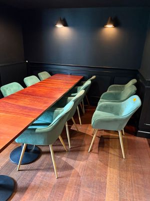 une longue table en bois avec des chaises vertes au milieu de la pièce