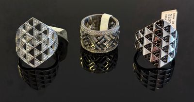 Trois bagues différentes sont présentées sur une table avec un fond noir.