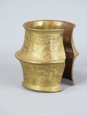 an old brass vase sitting on top of a table next to a white wall