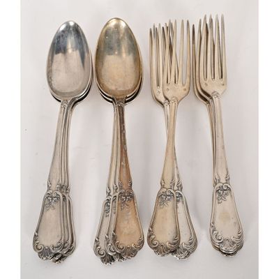 five silver spoons and two forks are lined up on a white surface