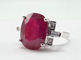 a close up of a ring with a red stone on a white surface
