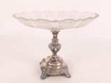 un plat ancien en argent posé sur un socle, sur fond blanc
