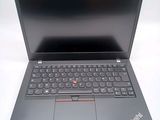 the laptop is open on a white surface and has a red button on the keyboard