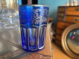 a blue glass sitting on top of a table next to a clock