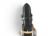 black leather watch strap with gold buckle on a white background