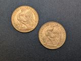 two gold coins, one of which is a rooster and the other of which is a rooster
