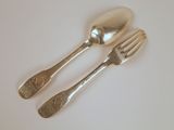 deux cuillères en argent et une fourchette posées sur une table blanche