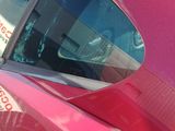 a red car parked in a parking lot with other cars in the background