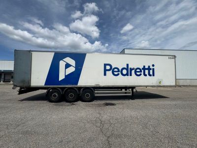 a white semi truck with a blue and white logo parked in front of a building