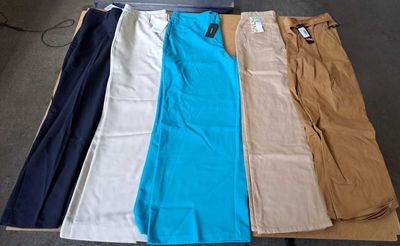 Plusieurs paires de pantalons sont disposées sur une table dans une pièce.