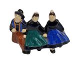 trois figurines représentant des personnes assises sur un banc