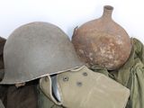 a pile of military items that include a helmet, jacket, and other items