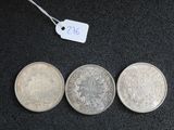 trois pièces d'argent posées les unes à côté des autres sur une surface noire