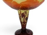 an orange and yellow glass bowl sitting on top of a wooden stand