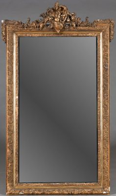 un miroir au cadre doré ouvragé sur fond gris