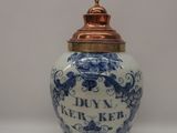 a blue and white vase with a gold lid on a table