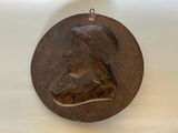 a bronze medallion of a man on a white surface