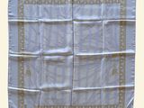 a close up of a white table cloth with a gold border