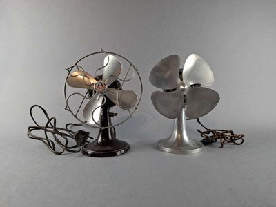 two metal fans sitting next to each other on a table