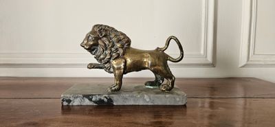 statue d'un lion posée sur un socle en marbre, elle-même posée sur une table en bois