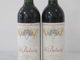 two bottles of red wine sitting next to each other on a table
