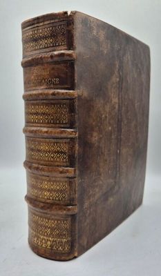 un vieux livre posé sur une table blanche, à côté d'une pile de livres