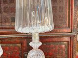 une lampe en verre posée sur une table, à côté d'un livre rouge