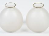 two white vases sitting next to each other on a white surface