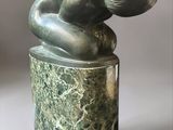 statue d'une femme tenant un bébé dans ses bras, posée sur un socle en marbre vert