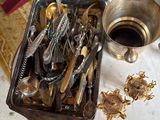 a tray full of silver spoons and other items on a table