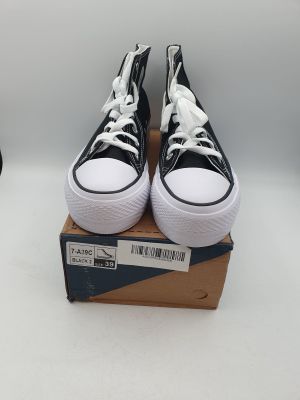 des baskets Converse noires et blanches avec des lacets blancs, posées sur une boîte en carton