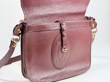 maroon leather cross body bag on white background with gold hardware