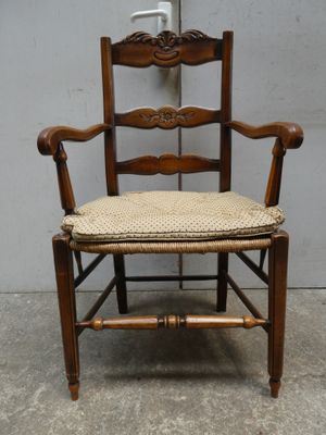 une chaise en bois avec un coussin posé dessus, devant un mur