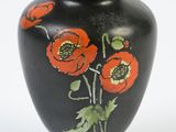 a black vase with red flowers painted on it