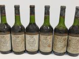 six bottles of wine are lined up in a row on a white surface