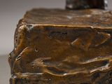 bronze statue of a man standing on a rock with his foot on the ground