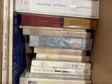 many books in a box that are stacked on top of each other