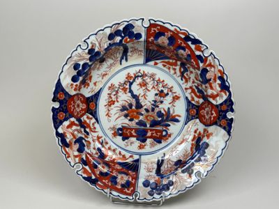 une assiette bleue et rouge ornée d'un oiseau et de fleurs