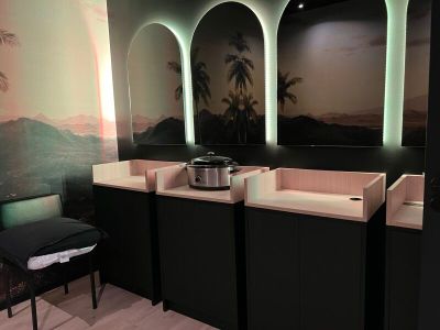 three sinks and a chair in a bathroom with a mural on the wall